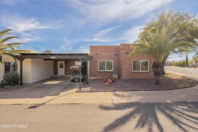 view of front facade with a carport, concrete driveway, brick siding, and stucco siding