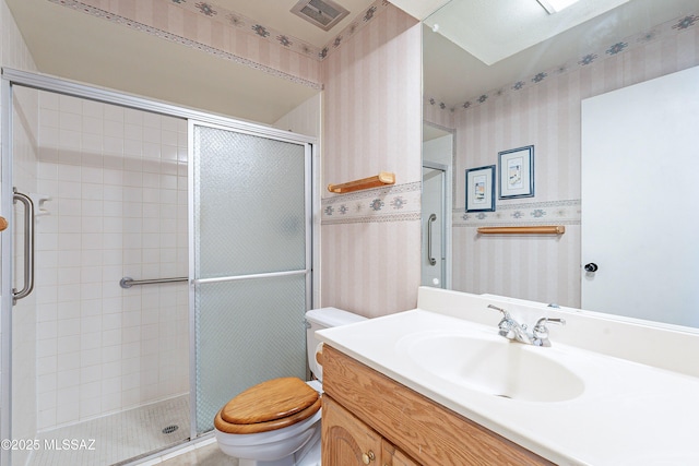 bathroom with a shower with door, vanity, and toilet