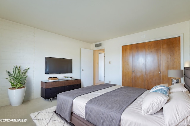 bedroom with a closet, visible vents, and light colored carpet