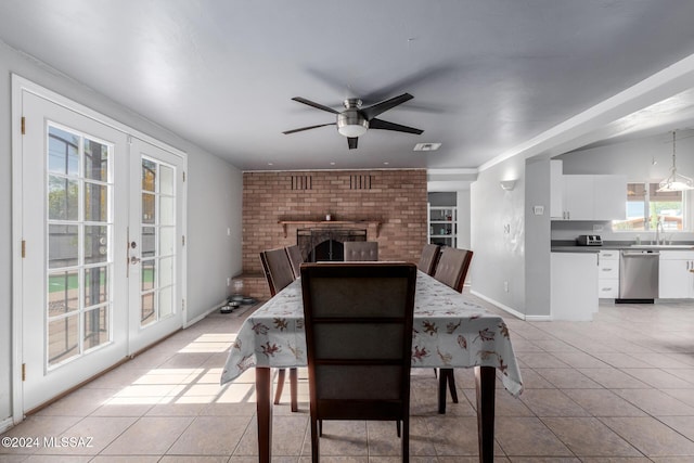 tiled dining space featuring sink, a fireplace, french doors, and ceiling fan