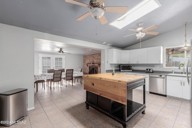 kitchen featuring pendant lighting, light tile patterned floors, sink, dishwasher, and white cabinets