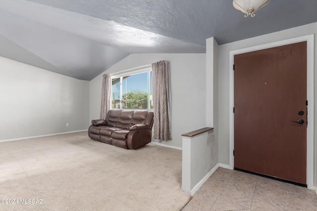 entrance foyer with vaulted ceiling, light carpet, and a textured ceiling