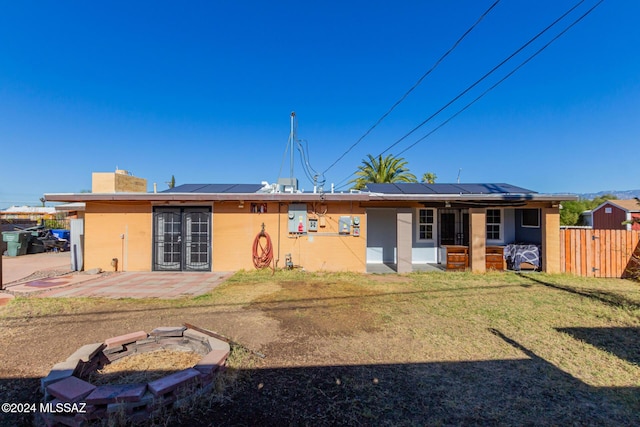 rear view of house with a lawn, a patio area, and solar panels