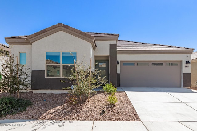 view of front of property featuring driveway, a tile roof, a garage, and stucco siding