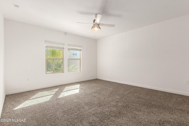 carpeted spare room featuring ceiling fan and baseboards