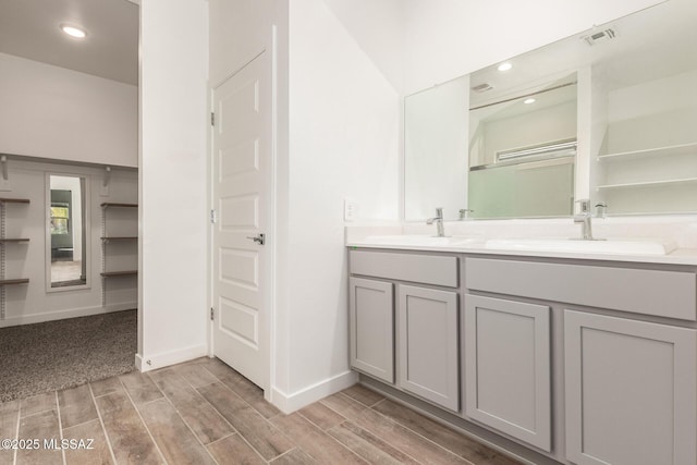 full bathroom featuring double vanity, wood finish floors, a sink, and visible vents