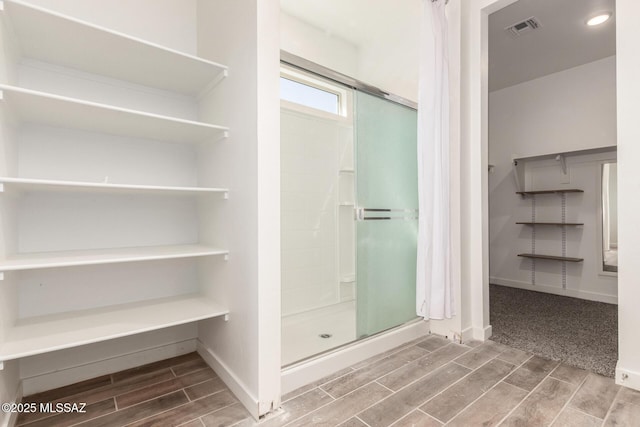 full bathroom featuring a stall shower, baseboards, visible vents, and wood finish floors