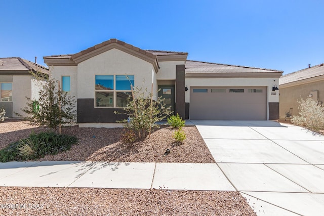 view of front of house featuring a garage, concrete driveway, a tiled roof, and stucco siding