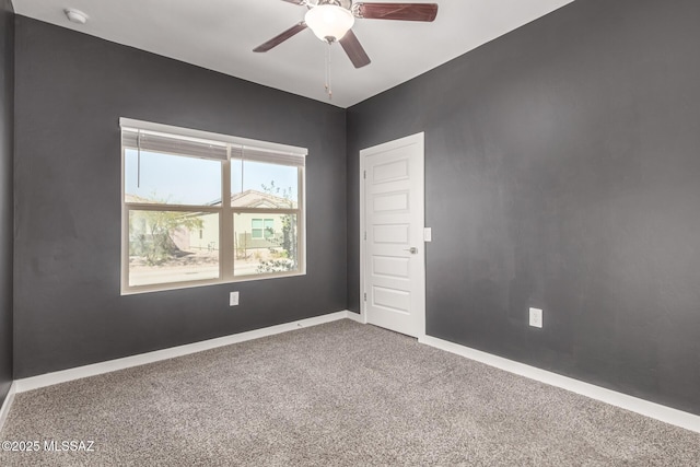 carpeted spare room with a ceiling fan and baseboards