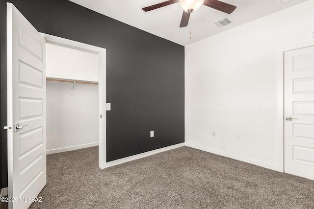 unfurnished bedroom with carpet, a walk in closet, a closet, visible vents, and baseboards