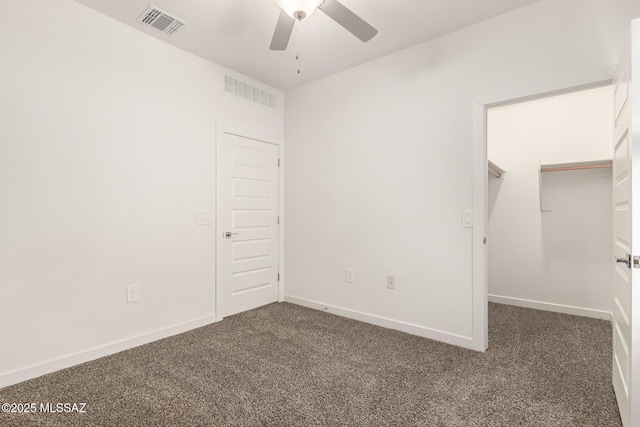 unfurnished bedroom featuring carpet, a walk in closet, and visible vents