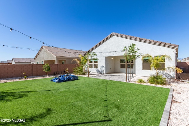 rear view of property featuring a yard, a patio, fence private yard, and stucco siding