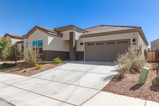 view of front of property featuring a tile roof, driveway, an attached garage, and stucco siding