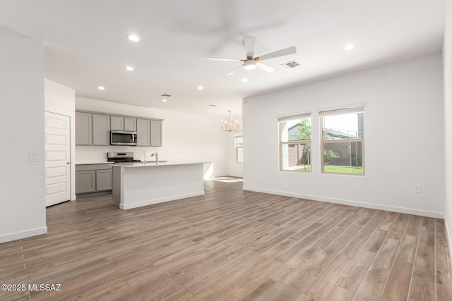 kitchen featuring visible vents, open floor plan, stainless steel appliances, gray cabinetry, and light wood-type flooring