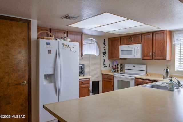 kitchen featuring sink, white appliances, kitchen peninsula, and a textured ceiling