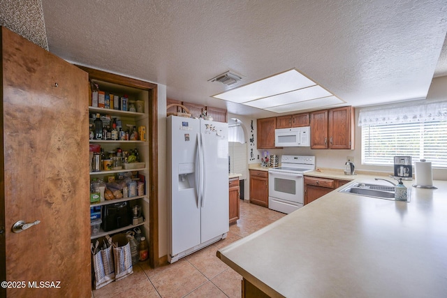 kitchen with white appliances, sink, a textured ceiling, and light tile patterned floors