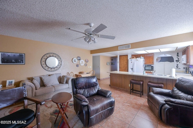 tiled living room featuring ceiling fan and a textured ceiling