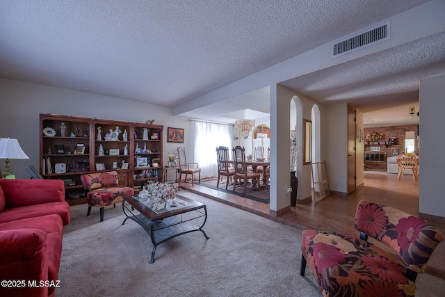 carpeted living room featuring an inviting chandelier and a textured ceiling