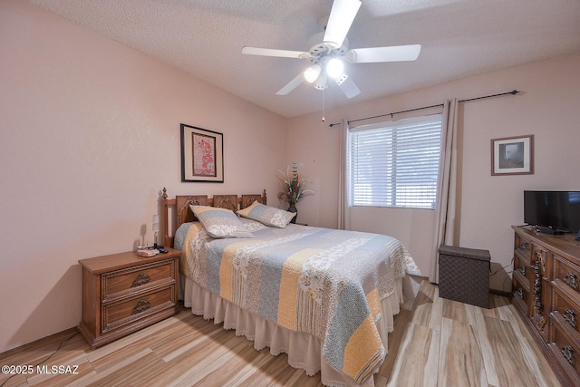 bedroom featuring ceiling fan, light hardwood / wood-style flooring, and a textured ceiling