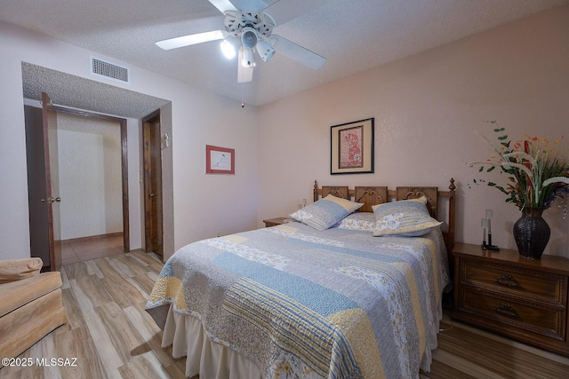 bedroom with ceiling fan, light hardwood / wood-style floors, and a textured ceiling