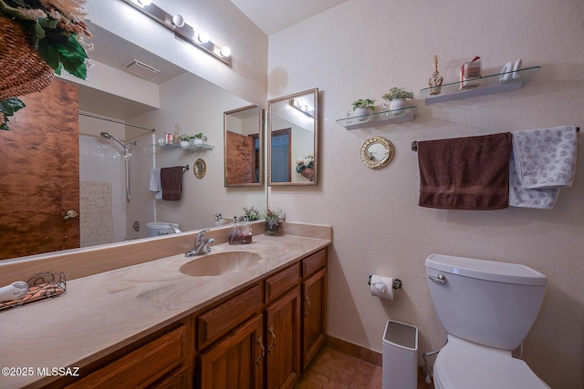 bathroom with tiled shower, tile patterned floors, vanity, and toilet