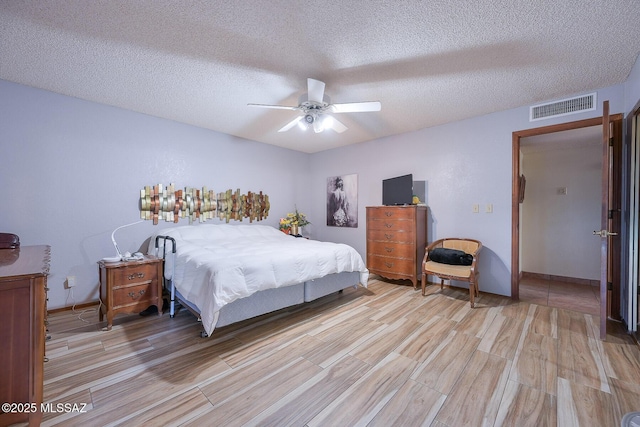 bedroom featuring ceiling fan, a textured ceiling, and light hardwood / wood-style floors