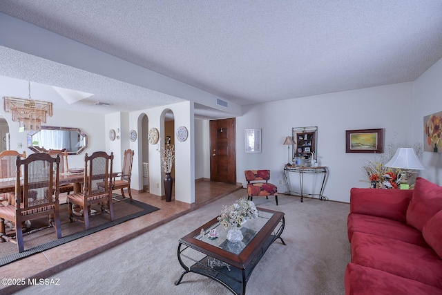 carpeted living room featuring a chandelier and a textured ceiling