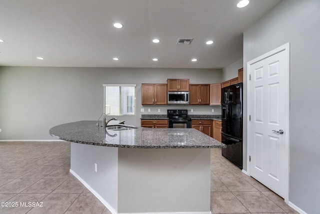 kitchen featuring light tile patterned floors, sink, an island with sink, and black appliances