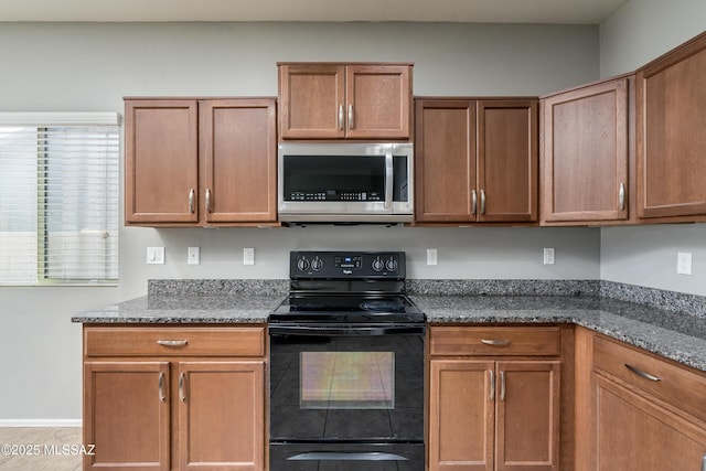 kitchen with black / electric stove and dark stone counters