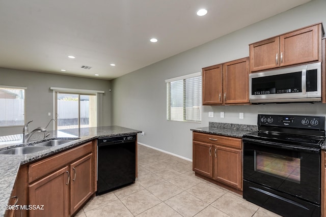 kitchen featuring light tile patterned floors, dark stone counters, sink, and black appliances