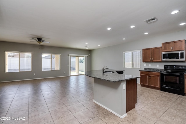 kitchen featuring sink, light tile patterned floors, an island with sink, black range with electric cooktop, and stone counters