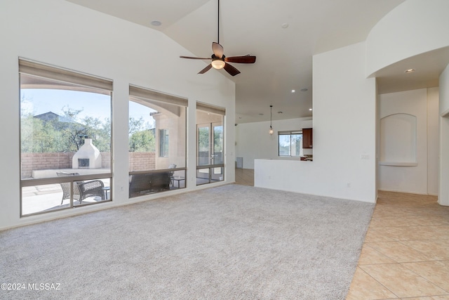 unfurnished living room with vaulted ceiling, ceiling fan, and light tile patterned flooring