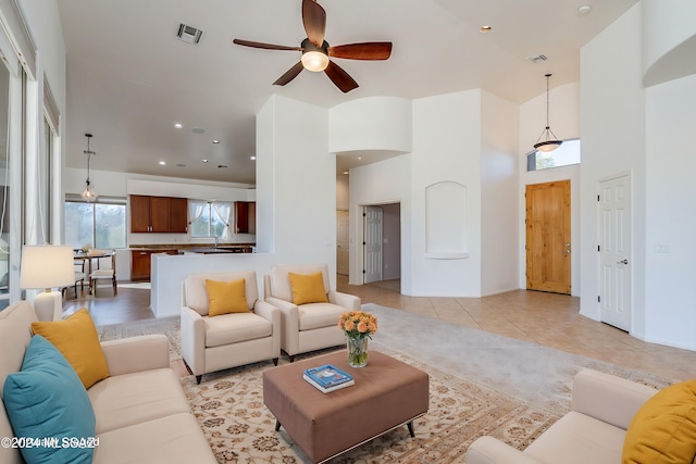 living room with light tile patterned flooring, a towering ceiling, and ceiling fan