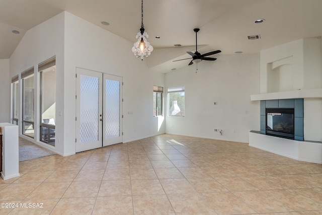 unfurnished living room featuring ceiling fan, a tiled fireplace, high vaulted ceiling, and light tile patterned floors