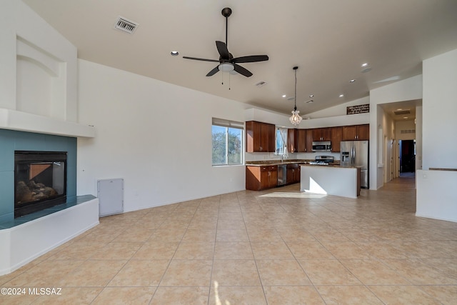 kitchen with a kitchen island, a fireplace, decorative light fixtures, light tile patterned floors, and stainless steel appliances