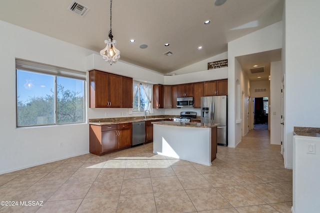 kitchen with sink, hanging light fixtures, stainless steel appliances, a center island, and vaulted ceiling