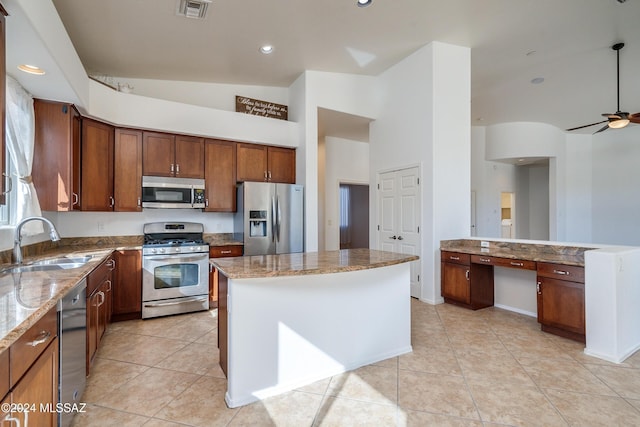 kitchen featuring light tile patterned flooring, sink, a center island, appliances with stainless steel finishes, and light stone countertops