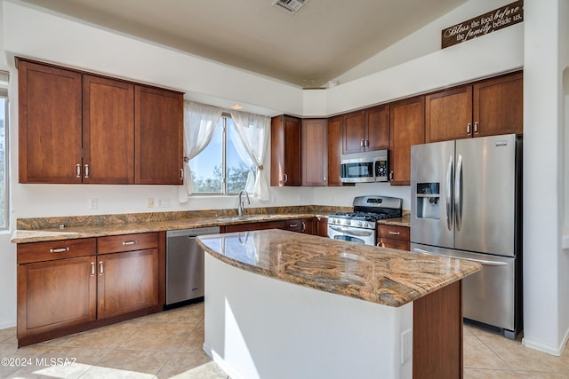 kitchen with vaulted ceiling, a kitchen island, sink, light stone counters, and stainless steel appliances