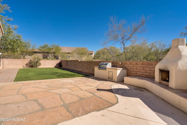 view of patio / terrace with exterior fireplace and an outdoor kitchen