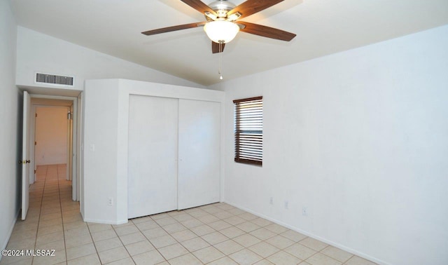 unfurnished bedroom featuring vaulted ceiling, light tile patterned floors, ceiling fan, and a closet