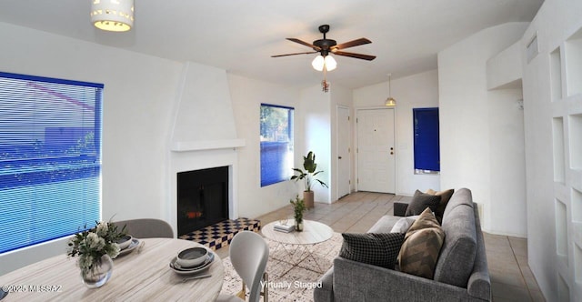 living room featuring vaulted ceiling, ceiling fan, and a fireplace