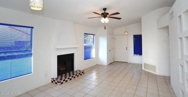 unfurnished living room featuring ceiling fan, a large fireplace, lofted ceiling, and light tile patterned floors