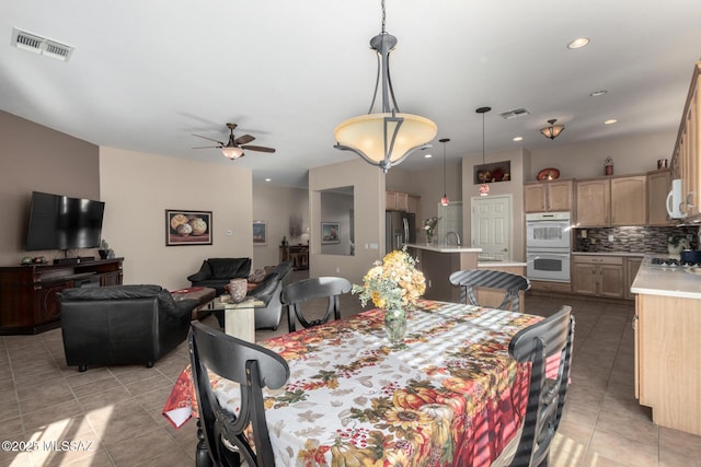 dining area with sink, light tile patterned floors, and ceiling fan