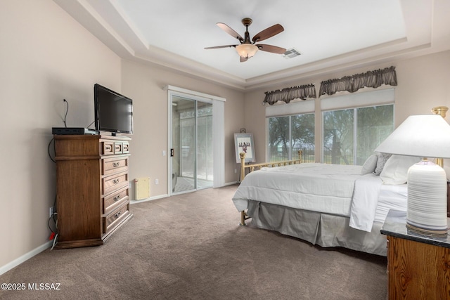 bedroom featuring dark colored carpet, ceiling fan, a tray ceiling, and access to outside