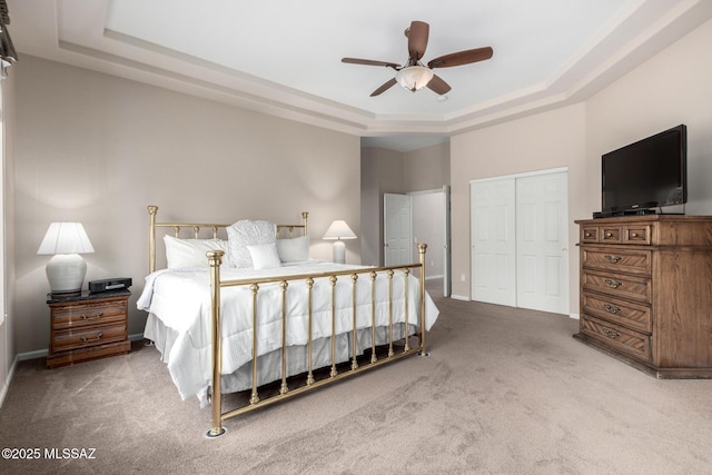 bedroom with ceiling fan, a tray ceiling, carpet, and a closet