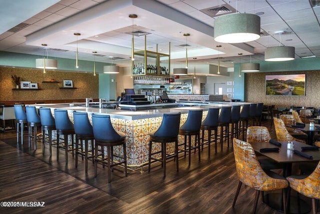 bar with a paneled ceiling, wood-type flooring, and decorative light fixtures