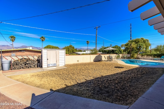 view of yard featuring a storage shed, a fenced in pool, and a patio