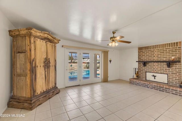 unfurnished living room featuring a fireplace, ceiling fan, and light tile patterned flooring