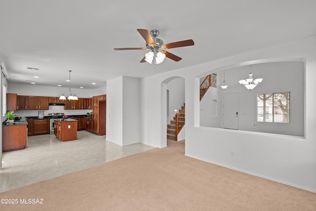 carpeted living room with ceiling fan with notable chandelier