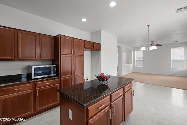 kitchen with a center island, hanging light fixtures, and dark stone countertops